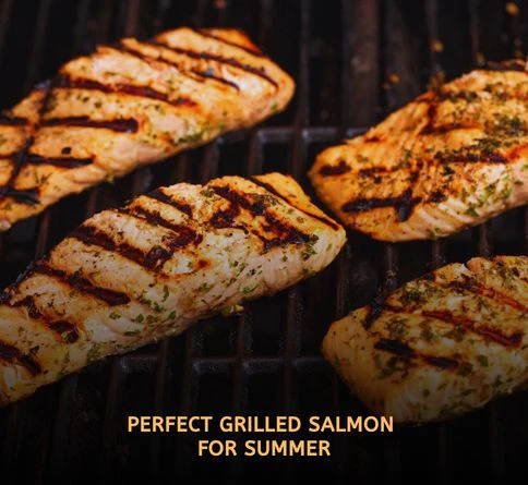 Fresh grilled salmon fillets topped with lemon slices and herbs cooking on an outdoor grill during a summer barbecue.