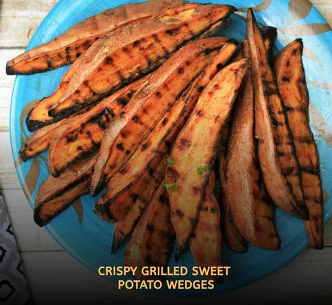Crispy grilled sweet potato wedges with smoky charred edges served fresh from an outdoor barbecue grill.