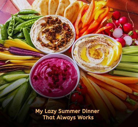 Hummus veggie board with pita bread, carrots, cucumbers, and olives arranged on a platter