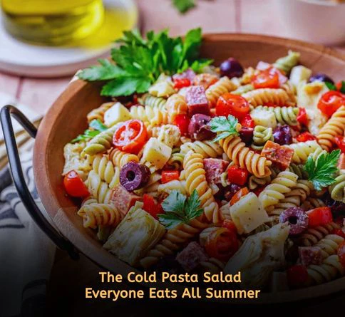 Cold pasta salad with rotini pasta olives tomatoes and parmesan cheese in a large bowl for refreshing summer lunches