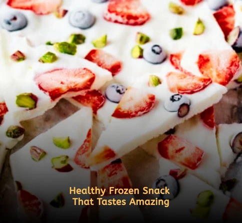 Frozen yogurt bark topped with mixed berries and nuts broken into pieces on parchment paper