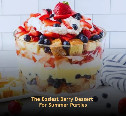 Mixed berry trifle layered with whipped cream strawberries blueberries and cake cubes in a glass bowl