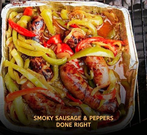 Italian sausages grilling beside colorful bell peppers and onions on a smoky outdoor summer barbecue grill.