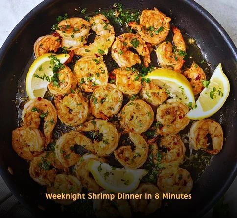 Lemon garlic shrimp cooked in a skillet and garnished with fresh lemon wedges.