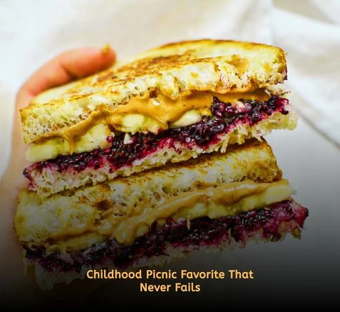 Classic peanut butter and jelly sandwich cut into halves on a picnic blanket