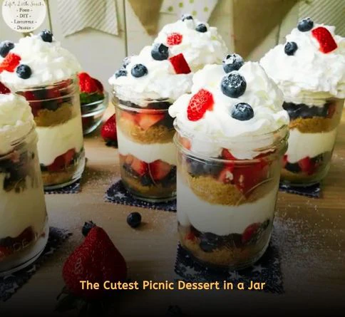Layered cheesecake dessert jars with graham crackers, cream filling, and cherry topping for a picnic.