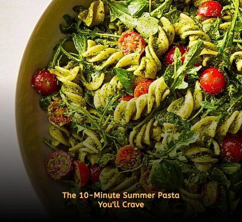 Cold pesto pasta salad with cherry tomatoes and parmesan cheese in a large serving bowl.