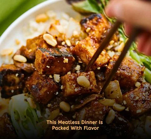 Crispy tofu served over rice and drizzled with spicy peanut sauce in a bowl.