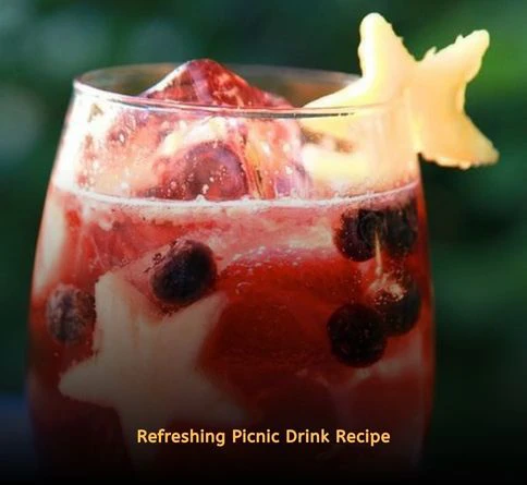 Sparkling fruit spritzer with berries and lime served in picnic glasses outdoors.