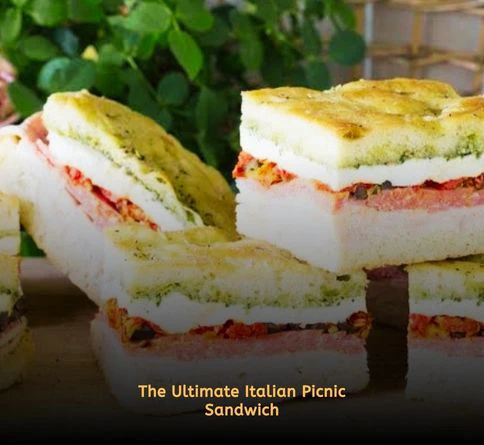Pressed Italian focaccia sandwich filled with pesto, meats, spinach, and roasted peppers wrapped in parchment paper.