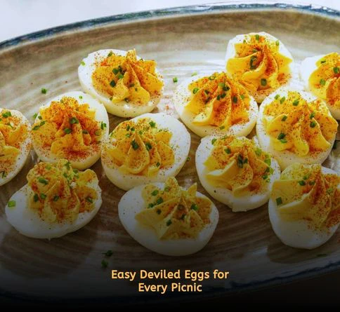 Homemade deviled eggs topped with paprika arranged on a serving tray outdoors