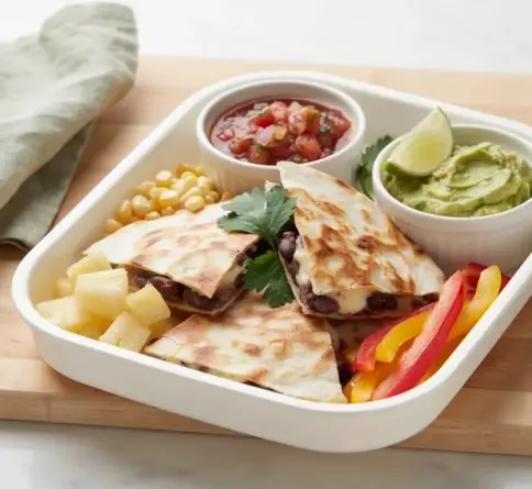 Bean and cheese quesadilla wedges with corn, peppers, pineapple, salsa, and guacamole in a bento box.