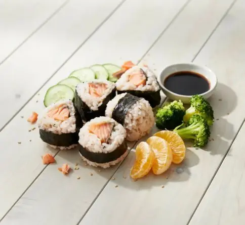 Cooked salmon rice ball bento with nori, cucumber, broccoli, and orange segments.