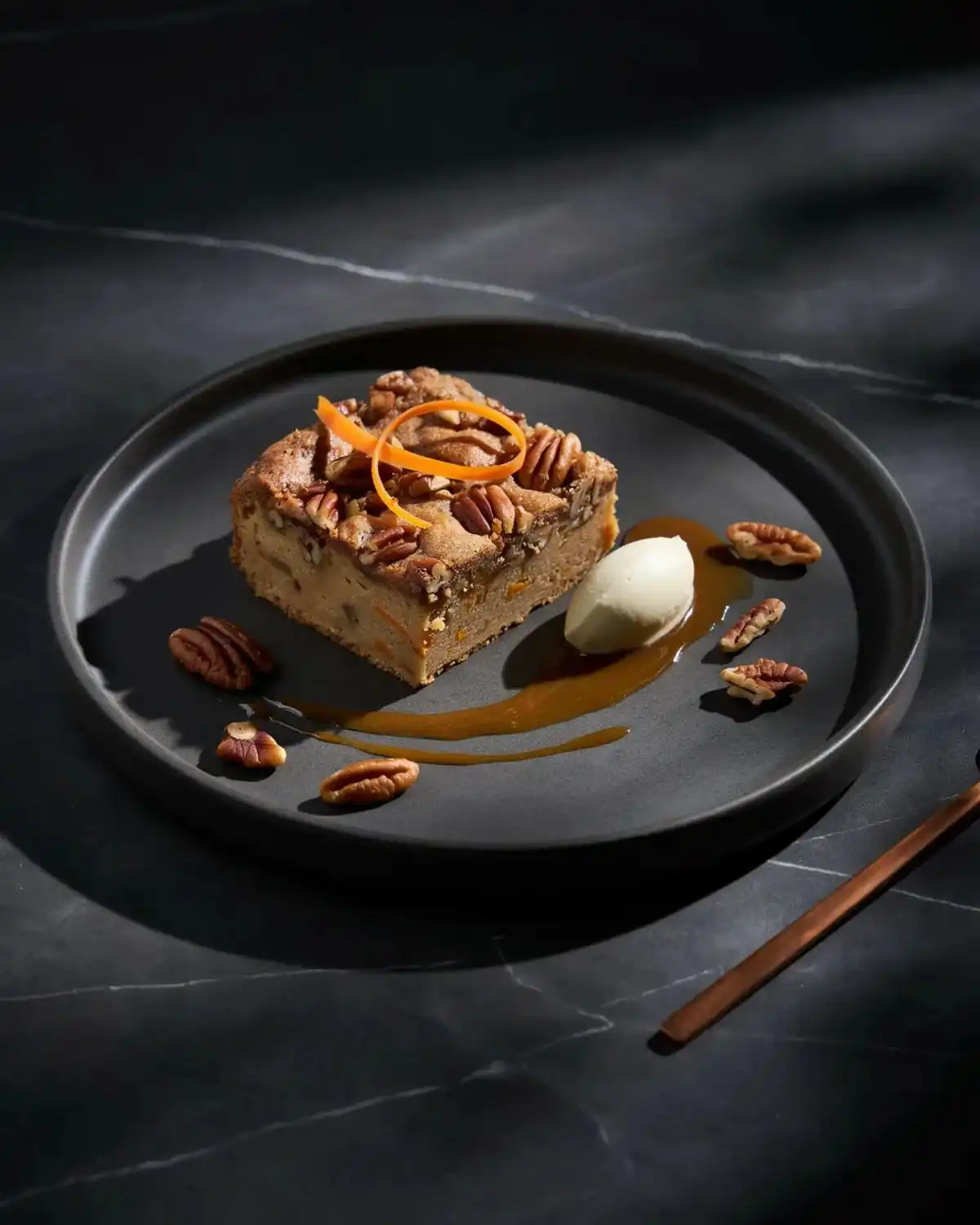 Brown butter pecan carrot cake cobbler plated with toasted pecans and caramel sauce.