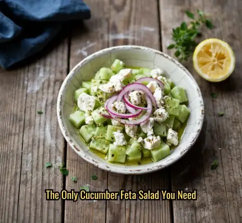  Classic Greek cucumber and feta salad with red onion and oregano in a ceramic bowl, drizzled with olive oil dressing.