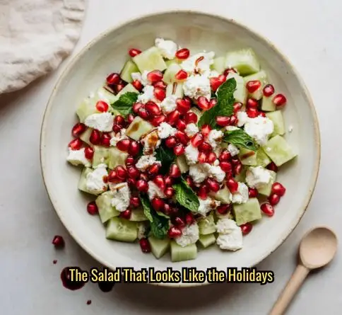 Pomegranate cucumber feta salad with ruby pomegranate seeds and pomegranate molasses drizzle in a ceramic bowl.
