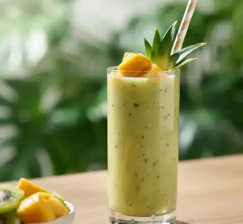 Tropical green mixed fruit smoothie with spinach, pineapple, and mango in a tall glass