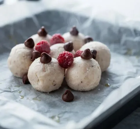 Frozen yogurt bites topped with chocolate chips and raspberries, a healthy summer dessert for kids
