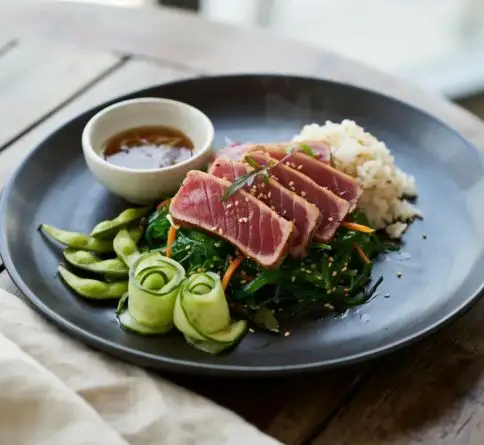 Seared Hawaiian ahi tuna steak with a pink center, sesame seeds, rice, and fresh vegetables.