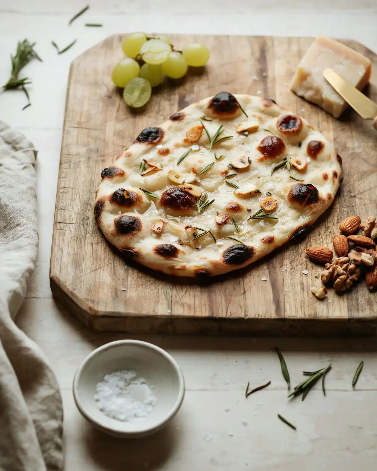 Blistered rosemary garlic flatbread served on a wooden cheese board