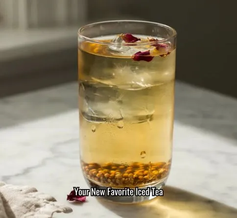  Iced green tea with rose petals and coriander seeds in a clear glass over ice.
