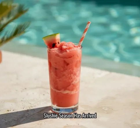 Watermelon coconut slushie in a glass with icy texture and a watermelon wedge garnish.