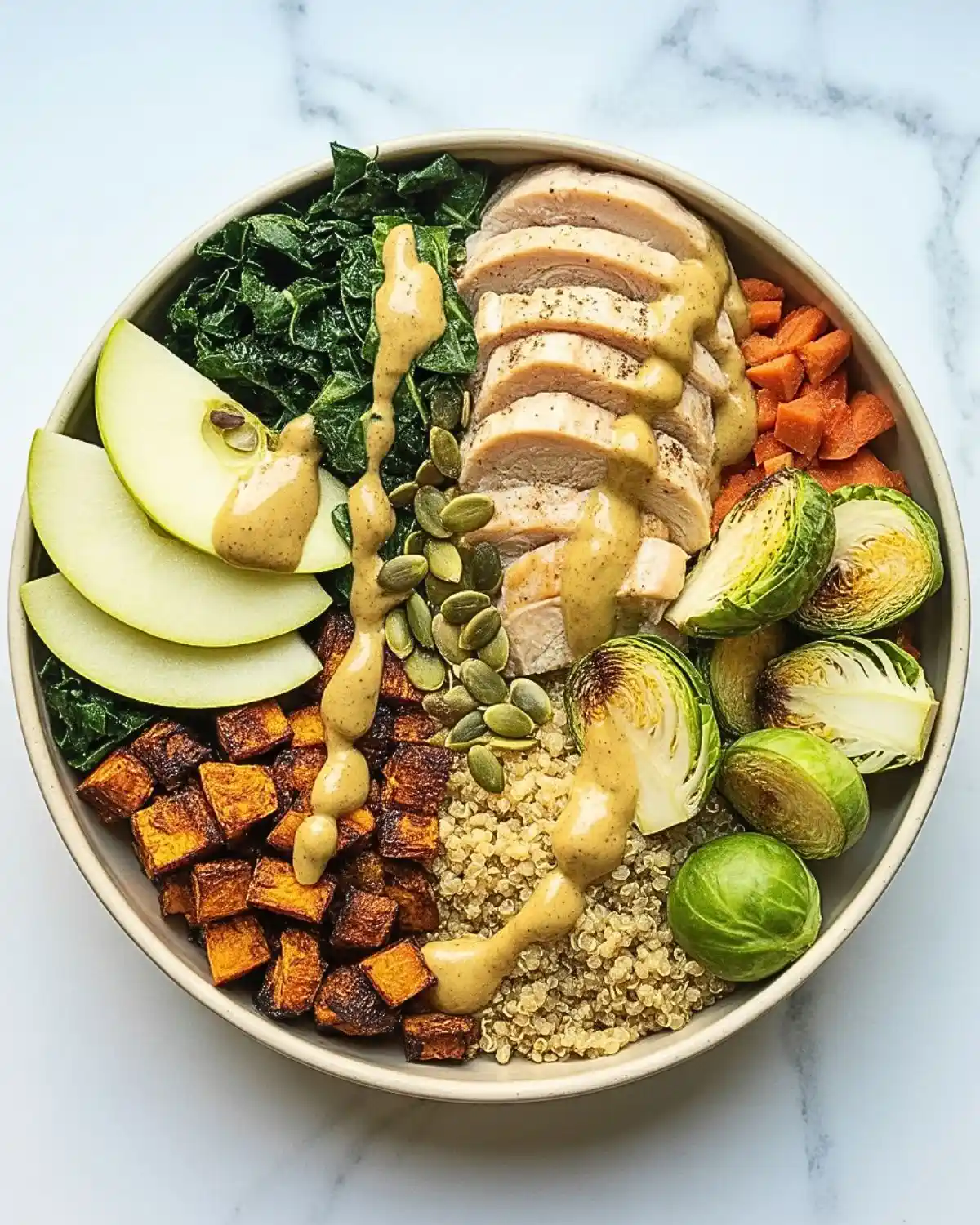 Chicken harvest grain bowl with quinoa, sweet potatoes, Brussels sprouts, kale, and apple.